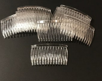 Può includere: Un set di pettini per capelli in plastica trasparente. I pettini sono tutti della stessa dimensione e forma, e hanno un design curvo. I pettini sono disposti in una pila su una superficie nera.