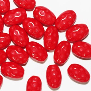 May include: A group of bright red oval-shaped beads with a textured surface. The beads are scattered on a white background.