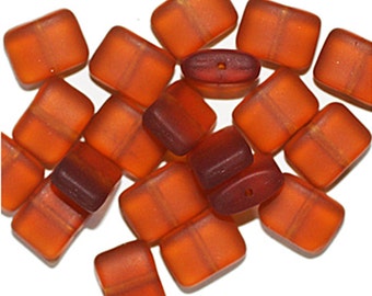 May include: A group of 18 small, square, opaque, amber-colored glass beads. The beads have a slightly frosted finish and are perfect for jewelry making.