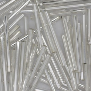 May include: A pile of clear glass rods, also known as glass strands, used for crafting and jewelry making.