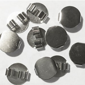 Peut inclure: Dix disques ronds en métal argenté avec un petit clip en métal sur le côté. Les disques sont lisses et brillants.