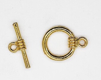 May include: Gold-toned metal toggle clasp with a round ring and a bar with a small loop. This clasp is used for necklaces, bracelets, and other jewellery.