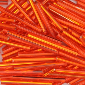 May include: A pile of orange glass rods, also known as glass beads, for crafting and jewelry making.