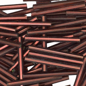 May include: A pile of brown glass beads, each bead is a long cylinder with a slightly iridescent finish.