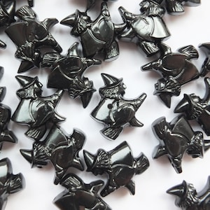 May include: A collection of black plastic witch buttons. Each button features a witch riding a broomstick. The buttons are glossy and have a 3D effect.