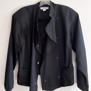 Könnte beinhalten: Schwarzer Blazer mit Stehkragen, doppelreihiger Knopfleiste und zwei Taschen. Das Etikett lautet "DAISY DICIOUS".