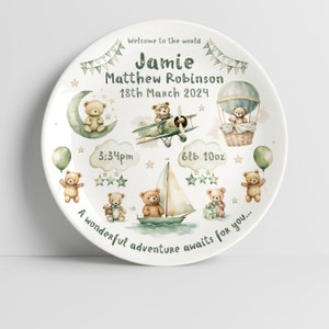 Puede incluir: Un plato de cerámica blanco con un diseño verde y marrón con osos de peluche, aviones y un globo aerostático. El plato está personalizado con el nombre "Jamie Matthew Robinson", la fecha "18 de marzo de 2024", la hora "3:34 pm" y el peso "6lb 10oz". El texto "Bienvenido al mundo" y "Una maravillosa aventura te espera..." también está incluido.