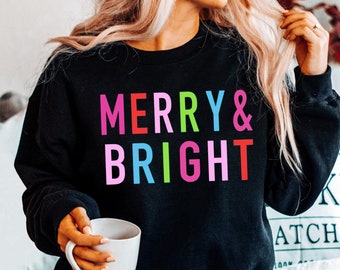 May include: A black sweatshirt with the text "MERRY & BRIGHT" in rainbow colors.