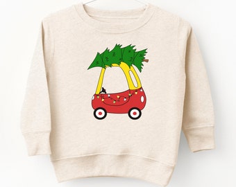 May include: A sand-colored sweatshirt with a Christmas tree on top of a red toy car with yellow accents. The car has Christmas lights strung around it. The sweatshirt has the text "SAND SWEATSHIRT FLASH SALE" at the bottom.