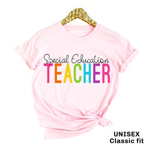 May include: Pink t-shirt with the text "Special Education Teacher" in rainbow colors. The shirt is a unisex classic fit.