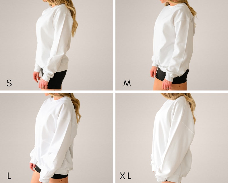 May include: Four white crewneck sweatshirts in different sizes: S, M, L, and XL. The sweatshirts are shown on a model from the side, with the sleeves rolled up.