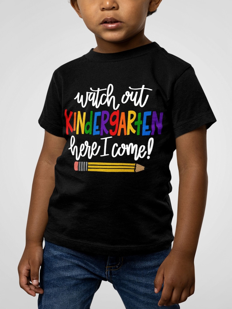 May include: A black t-shirt with the text "Watch out Kindergarten here I come!" in rainbow colours and a yellow pencil with a red eraser.