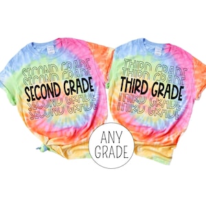 Pu&ograve; includere: Due magliette tie-dye con il testo "Second Grade" e "Third Grade" stampato su di esse. Le magliette sono un arcobaleno di colori, tra cui rosa, arancione, giallo, verde e blu.