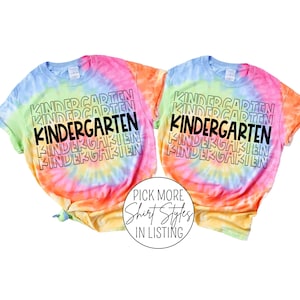 Pu&ograve; includere: Due magliette tie-dye con la parola "KINDERGARTEN" ripetuta in uno schema sovrapposto. Le magliette sono un arcobaleno di colori, tra cui rosa, arancione, giallo, verde e blu.