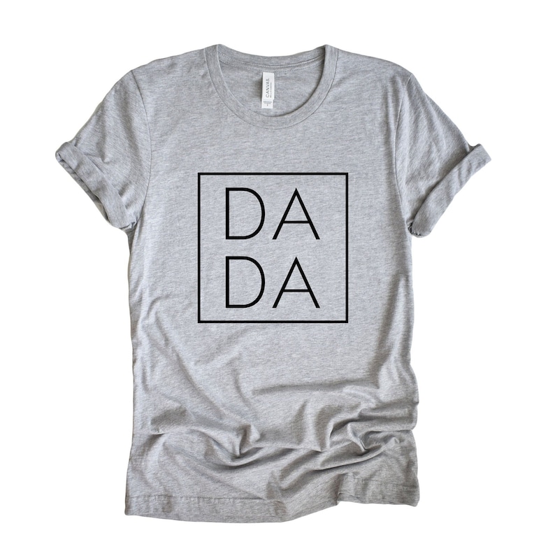 Puede incluir: Camiseta gris con un cuadrado negro y el texto "DA DA" dentro del cuadrado.
