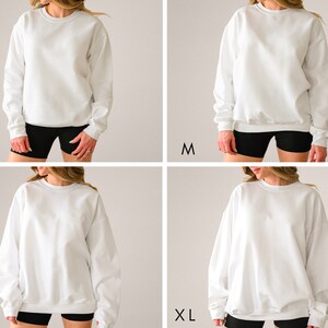 May include: Four white crewneck sweatshirts in different sizes: S, M, L, and XL. The sweatshirts are shown on a model wearing black shorts.