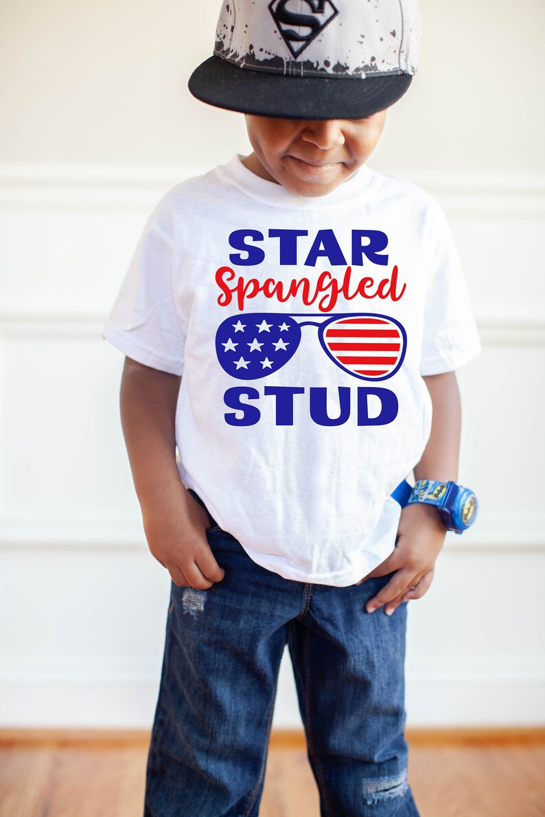 May include: A white t-shirt with a blue and red graphic of sunglasses with stars and stripes. The text "STAR Spangled STUD" is printed on the shirt.