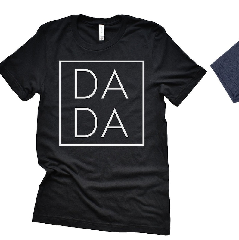 Puede incluir: Camiseta negra con un cuadrado blanco que contiene el texto "DA DA" en una fuente simple y moderna.