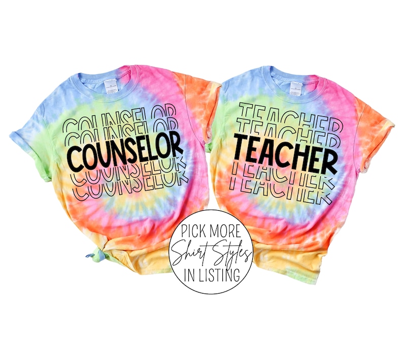 May include: Two tie-dye t-shirts with the words "COUNSELOR" and "TEACHER" printed in black on a rainbow background.