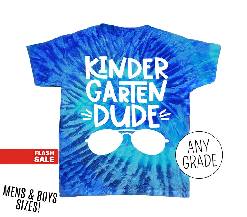 Op de afbeelding: Blauw tie-dye T-shirt met de witte woorden "KINDERGARTEN DUDE" en een witte zonnebrilafbeelding. Het shirt heeft ook de woorden "ANY GRADE" in een witte cirkel. Een rode banner leest "FLASH SALE".