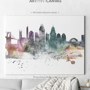 May include: A watercolour painting of a city skyline in shades of purple, teal, and pink. The canvas art piece is labelled "ARTPRINTCANVAS" and "US made solid pine canvas". The photo shows a 122x91 cm size.