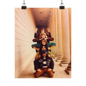May include: A vintage poster featuring a group of people stacked on top of each other in a pyramid formation. The people are wearing various outfits, including jackets, shirts, and pants. The background includes columns and a wall.