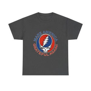 May include: Dark gray t-shirt featuring a Steal Your Face skull design with the text "MAKE AMERICA GRATEFUL AGAIN!" in a circular pattern. The graphic includes red, blue, and white colors.