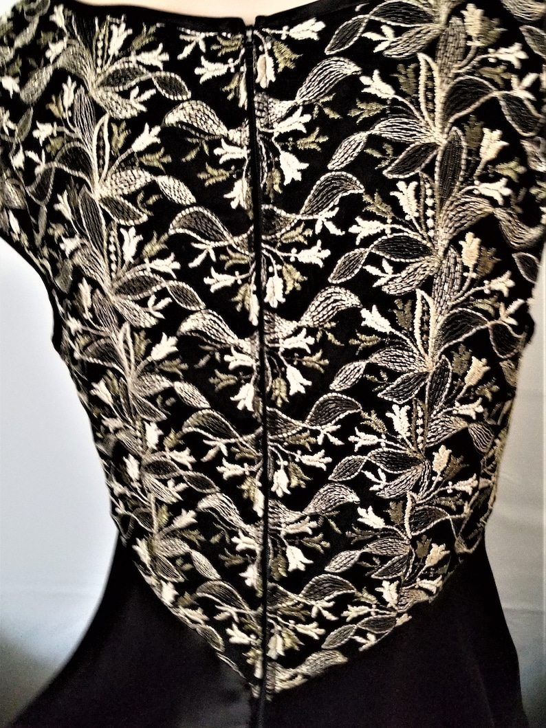以下が含まれることがあります： 白と金の糸で花柄の刺繍が施された、黒いノースリーブドレスです。