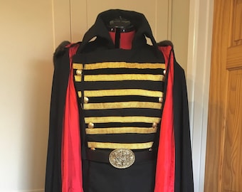 May include: A black and red costume with gold trim. The costume features a long black cape with a red lining, a black jacket with gold stripes, and a black belt with a large silver buckle.