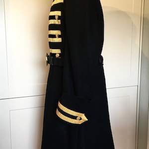 May include: A black long coat with gold trim on the sleeves and front. The coat has a high collar and a belt.
