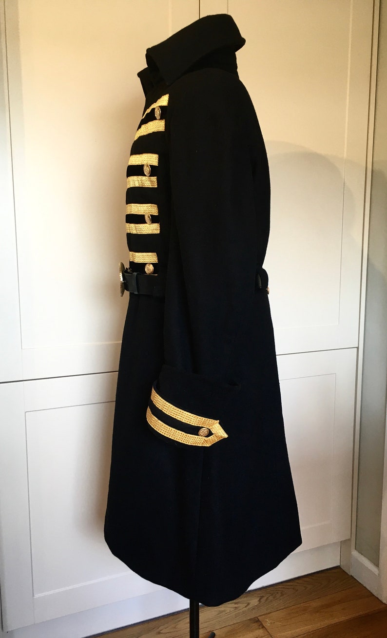 May include: A black long coat with gold trim on the sleeves and front. The coat has a high collar and a belt.