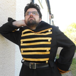 May include: A black coat with gold trim and buttons. The coat has a striped pattern on the front and a belt around the waist.