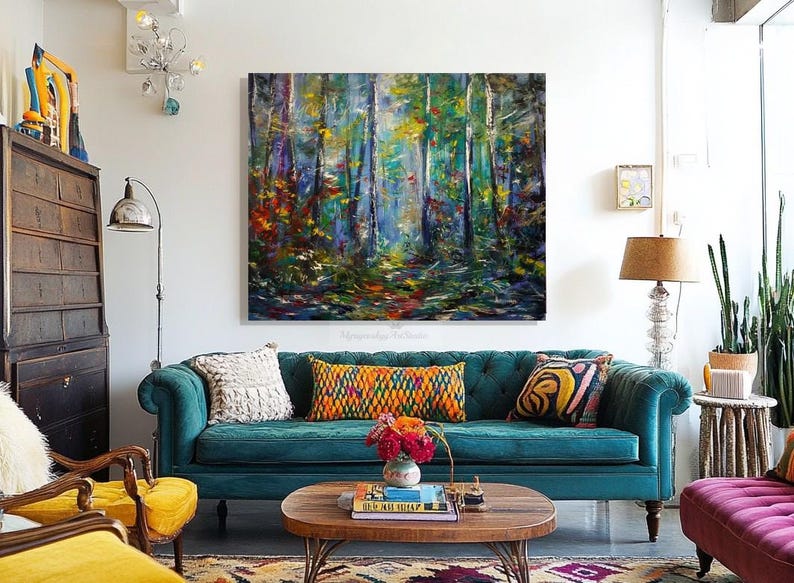 Puede incluir: Un sof&aacute; de terciopelo azul turquesa con una variedad de cojines coloridos, una mesa de centro con un libro y un jarr&oacute;n de flores, y una pintura de una escena de bosque colorida colgada en la pared.