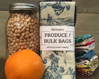 May include: Reusable produce and bulk bags made from upcycled scrap fabrics. The bags are printed with a blue and white floral pattern. A jar of chickpeas, an orange, and a stack of fabric scraps are also in the image.