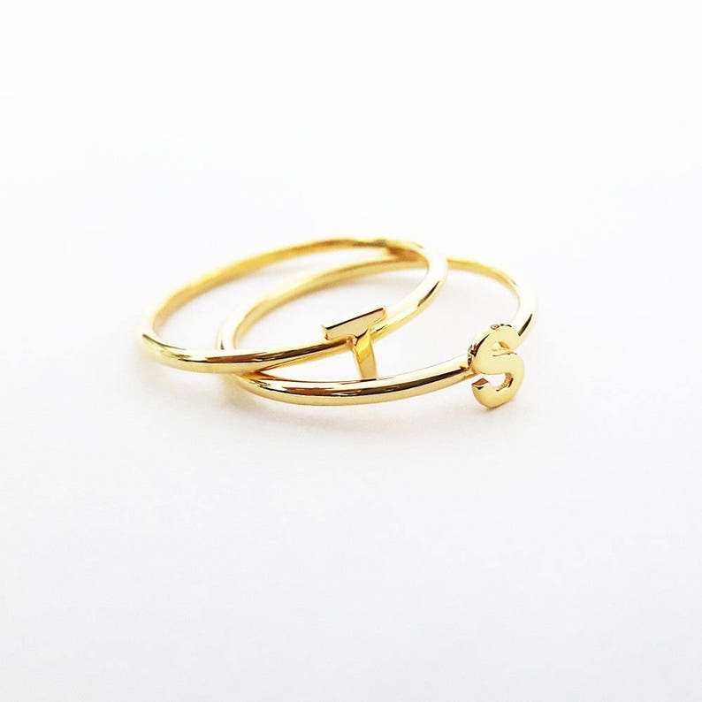 K&ouml;nnte beinhalten: Zwei goldene Ringe, einer mit dem Buchstaben "T" und der andere mit dem Buchstaben "S", liegen &uuml;bereinander.