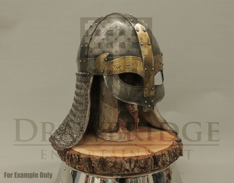 Op de afbeelding: Een zilveren Vikinghelm met een gouden rand en een kettingbaard. De helm staat op een houten standaard.