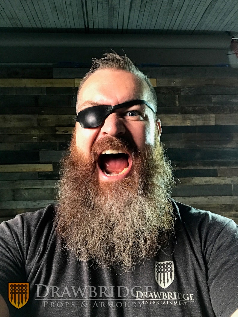 Drawbridge Props and Armoury, Levi, with long beard and short hair, wearing a black leather eyepatch on right eye.