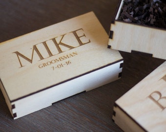 Może przedstawiać: Drewniana skrzynka z wygrawerowanym imieniem "MIKE" na górze, wraz z napisem "GROOMSMAN" i datą "7-01-16".