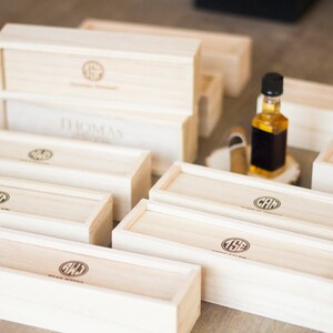May include: A collection of wooden boxes with personalized initials and the text "Custom Engraved" on the top. The boxes are arranged in a staggered pattern on a wooden surface.