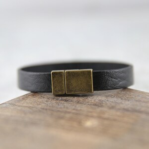 May include: A black leather bracelet with a brass magnetic clasp.