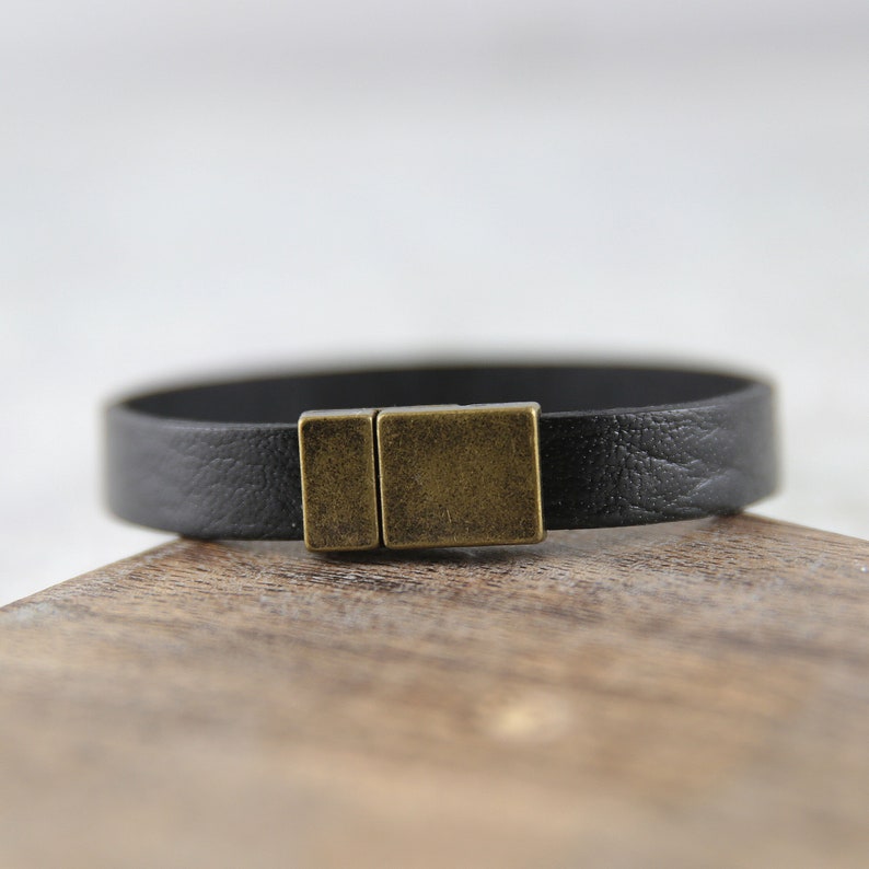 May include: A black leather bracelet with a brass magnetic clasp.