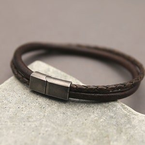 May include: A brown leather bracelet with a braided design and a silver magnetic clasp.