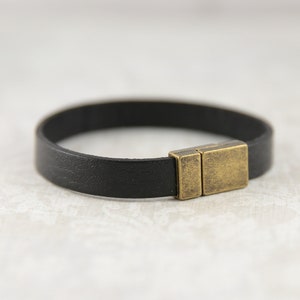 May include: A black leather bracelet with a brass magnetic clasp.