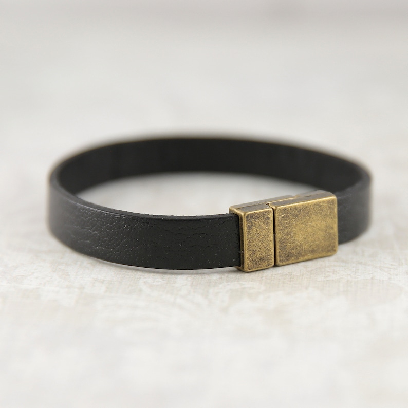May include: A black leather bracelet with a brass magnetic clasp.