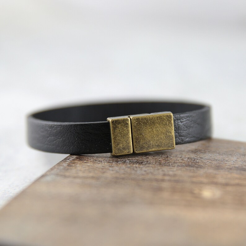 May include: A black leather bracelet with a brass magnetic clasp.