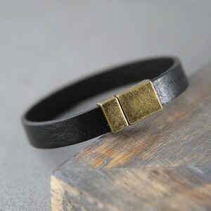 May include: A black leather bracelet with a brass magnetic clasp.