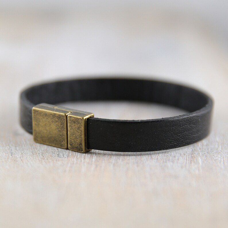 May include: A black leather bracelet with a brass magnetic clasp.