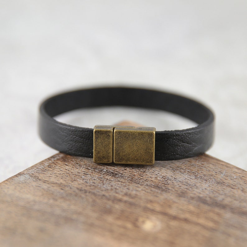 May include: A black leather bracelet with a brass magnetic clasp.