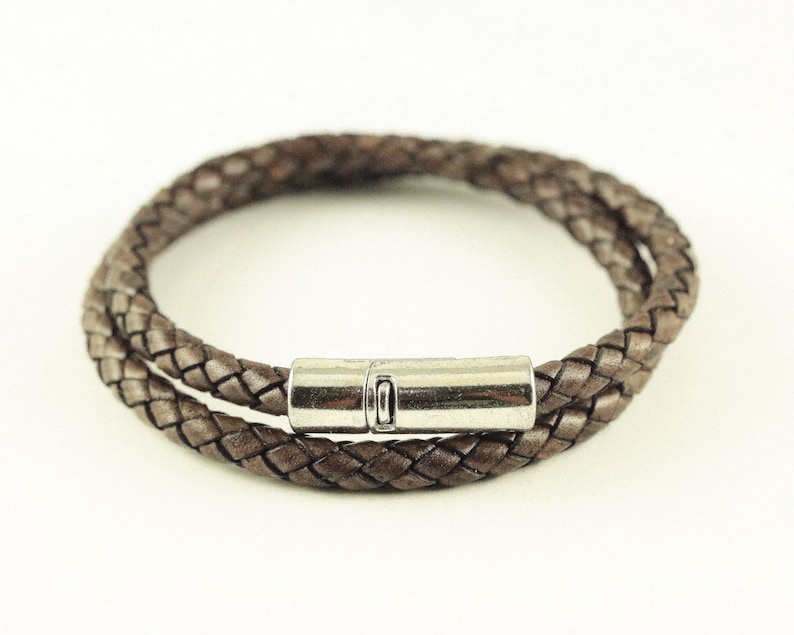 Puede incluir: Un brazalete de cuero marr&oacute;n con cierre magn&eacute;tico plateado.