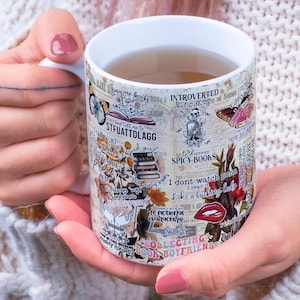 May include: White ceramic mug decorated with book-themed graphics, including butterflies, books, and text. The mug features phrases like "Introverted but willing" and "Collecting book boyfriends."